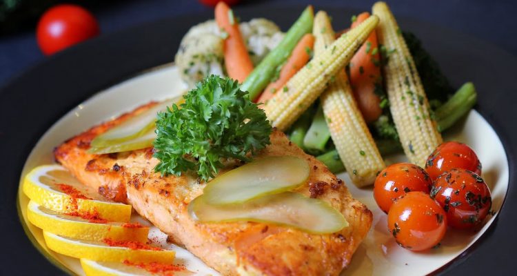 A beautifully plated salmon dish with fresh vegetables and lemon slices, perfect for a gourmet meal.